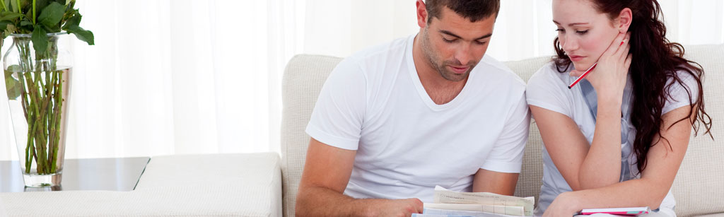 Couple sitting on a couch looking at  all of their household bills
