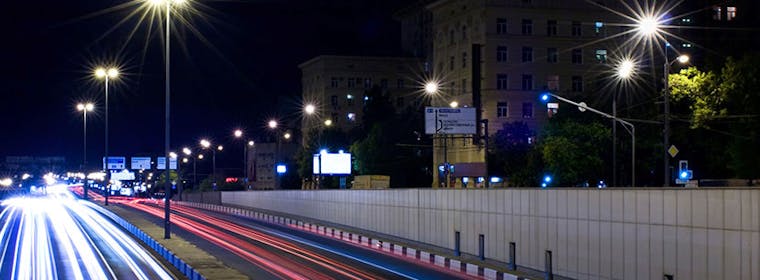 Dual carriageway in city at night with lights from cars 