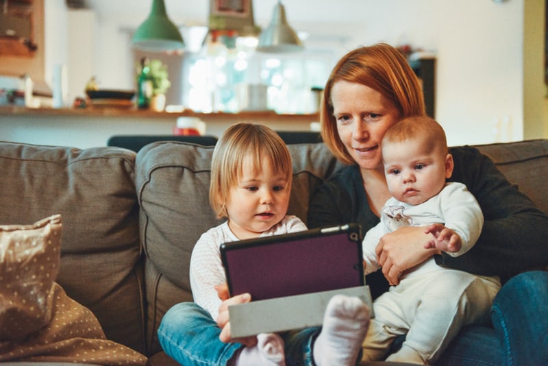 Mum with baby and toddler on sofa with ipad