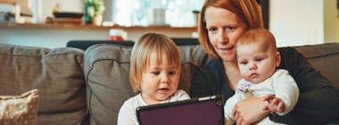 Mum with baby and toddler on sofa with ipad