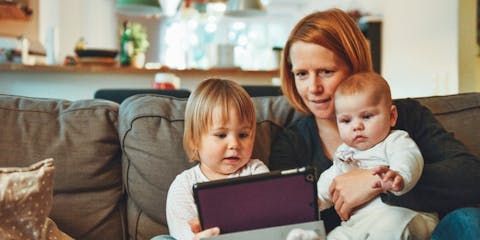 Mum with baby and toddler on sofa with ipad