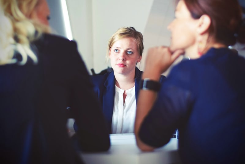 Woman seated at desk facing two other women